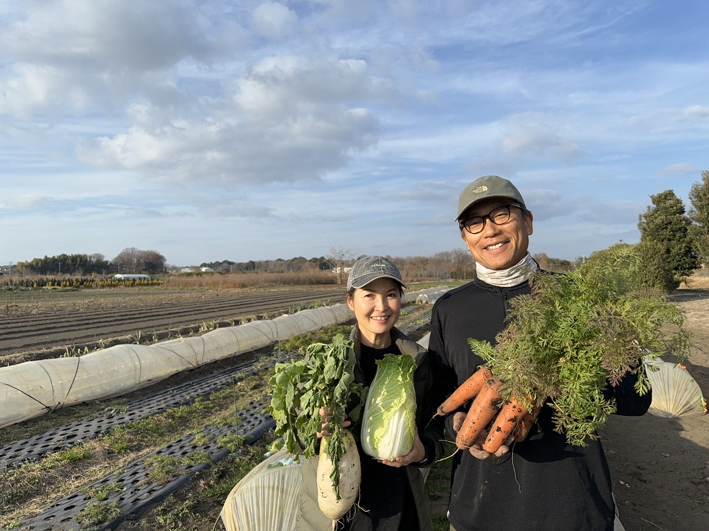 野菜を手に畑に立つKADO FARMの2人